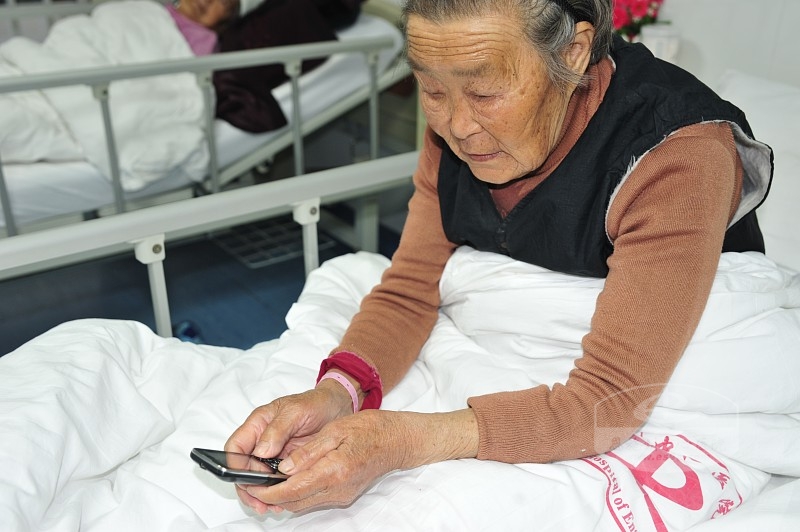 91岁的刘昌菊老人在摘去纱布后自己自如的翻看手机